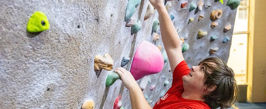 Male student climbing the rock wall.